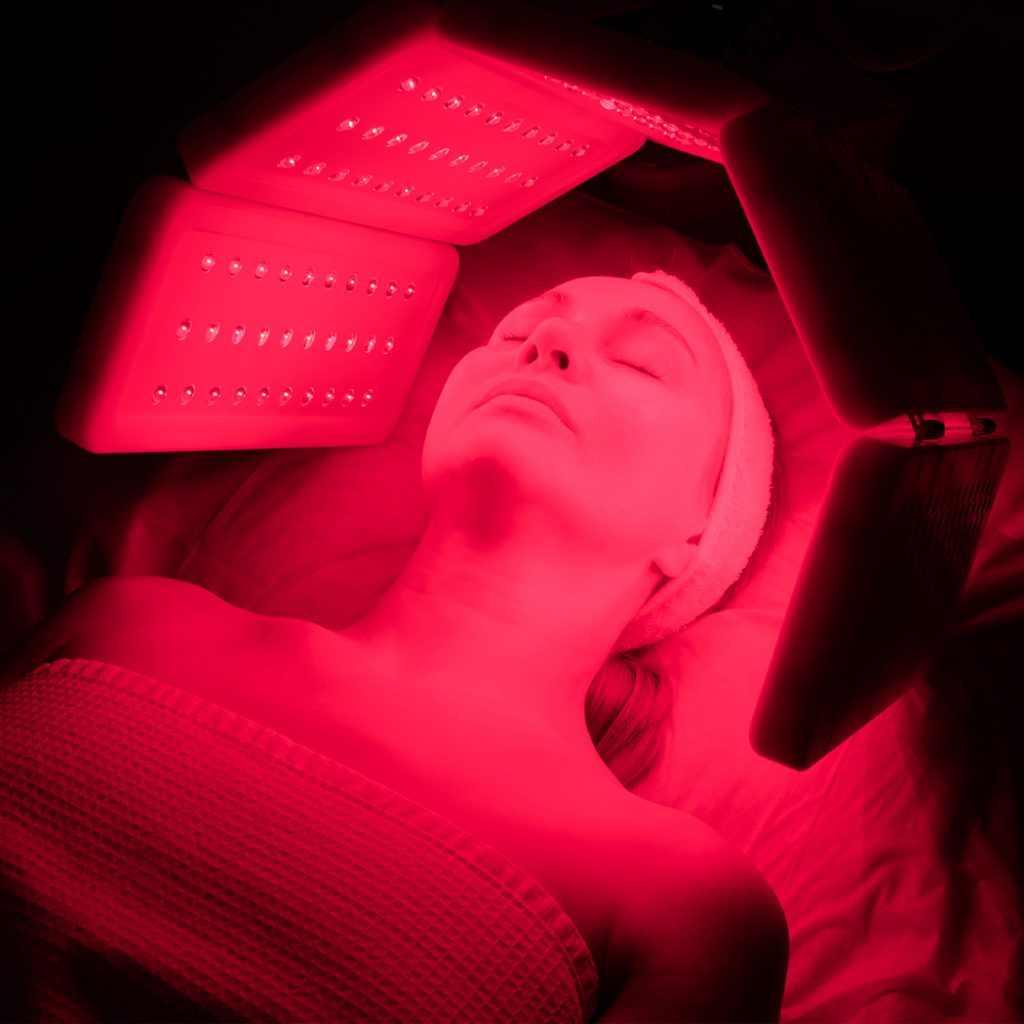 Woman laying down with red lights around her face