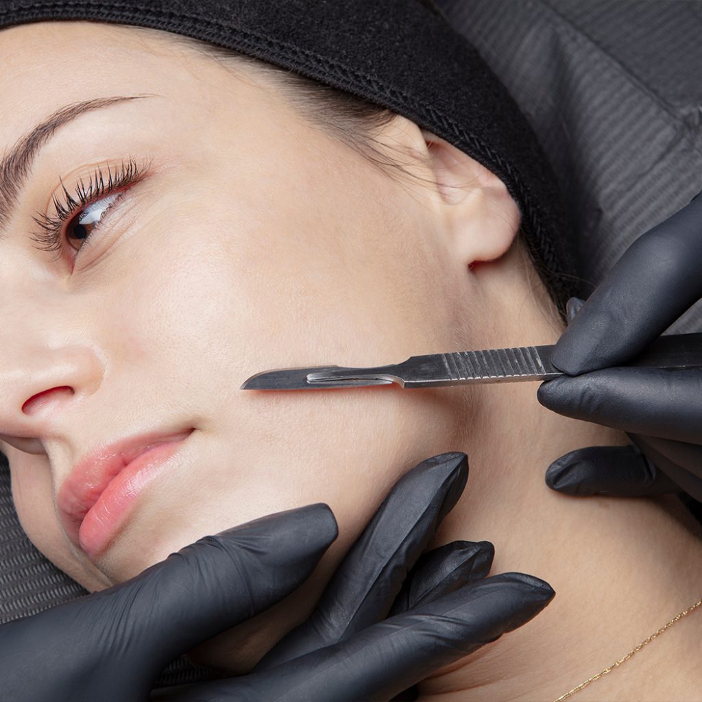 Woman laying and a doctor holding a scalpel in front of her face
