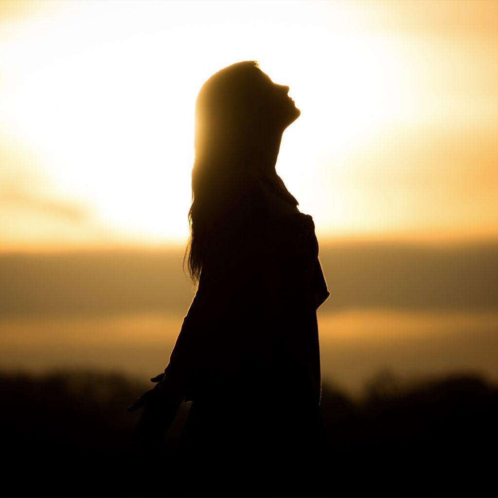 Woman standing while sun is setting on the background